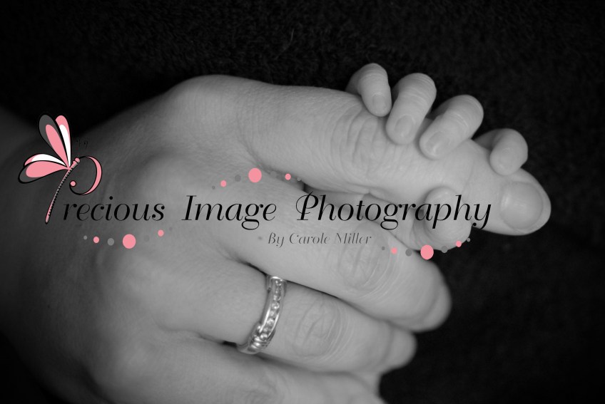 moms hand with newborns hand wrapped around