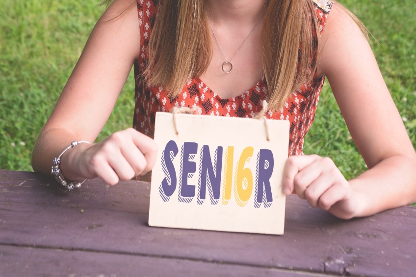 girl holding senior sign in school colors