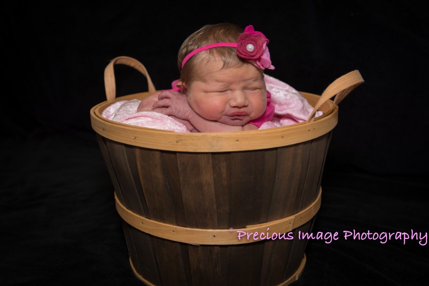 newborn girl wearing headband in basket