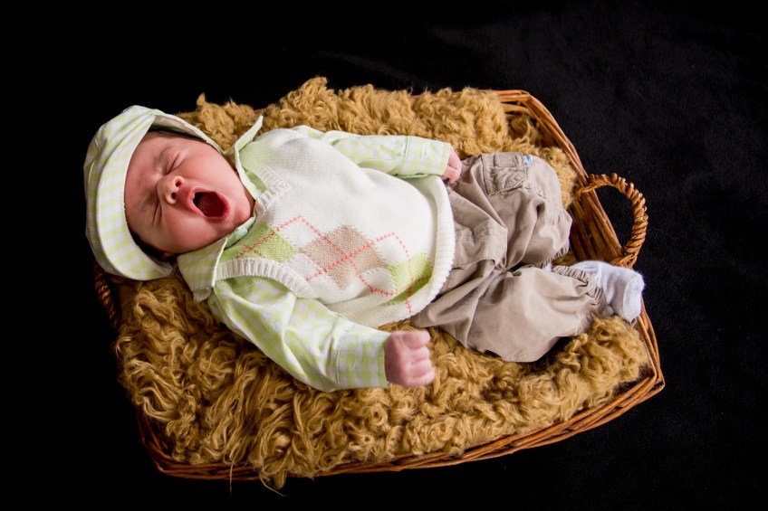 newborn boy in a basket yawning
