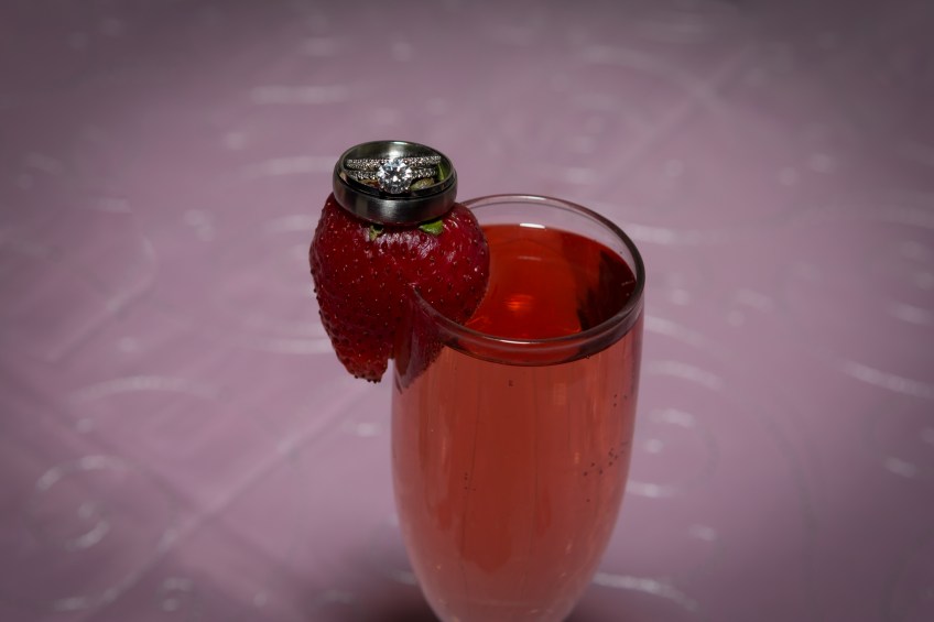 wedding rings on strawberry champagne glass