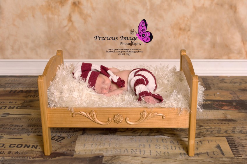 baby boy in bed on wood floor backdrop