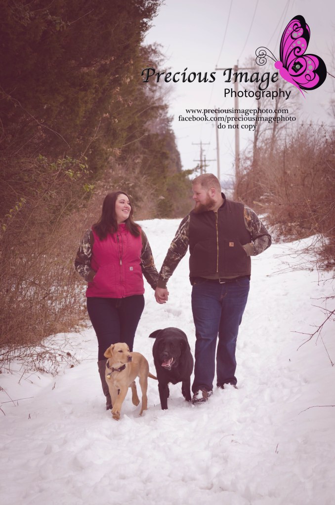 engagement couple with dogs in the snowy woods